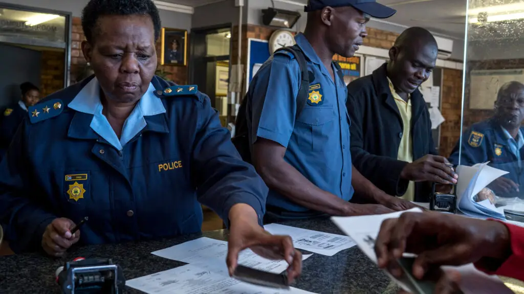 A South African police officer processing paperwork for a police clearance certificate application, relevant for South Africans applying from Canada.