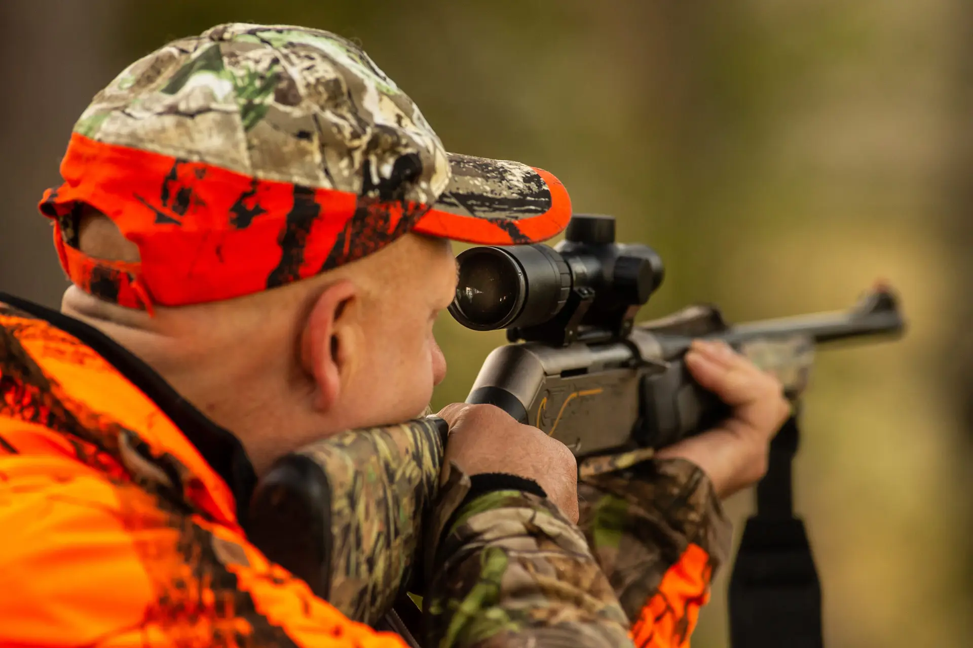 A hunter aiming a rifle in the bush, demonstrating legal and responsible firearm use in Canada.