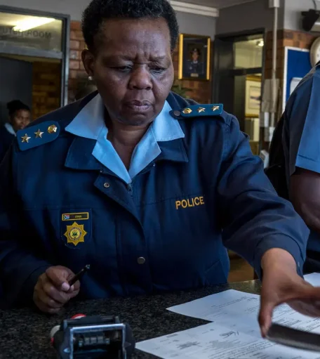 A South African police officer processing paperwork for a police clearance certificate application, relevant for South Africans applying from Canada.